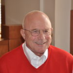 A man in red sweater and white shirt smiling.